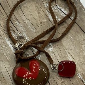 Round glass pendant w/red heart on leather rope approx 16”. back is signed